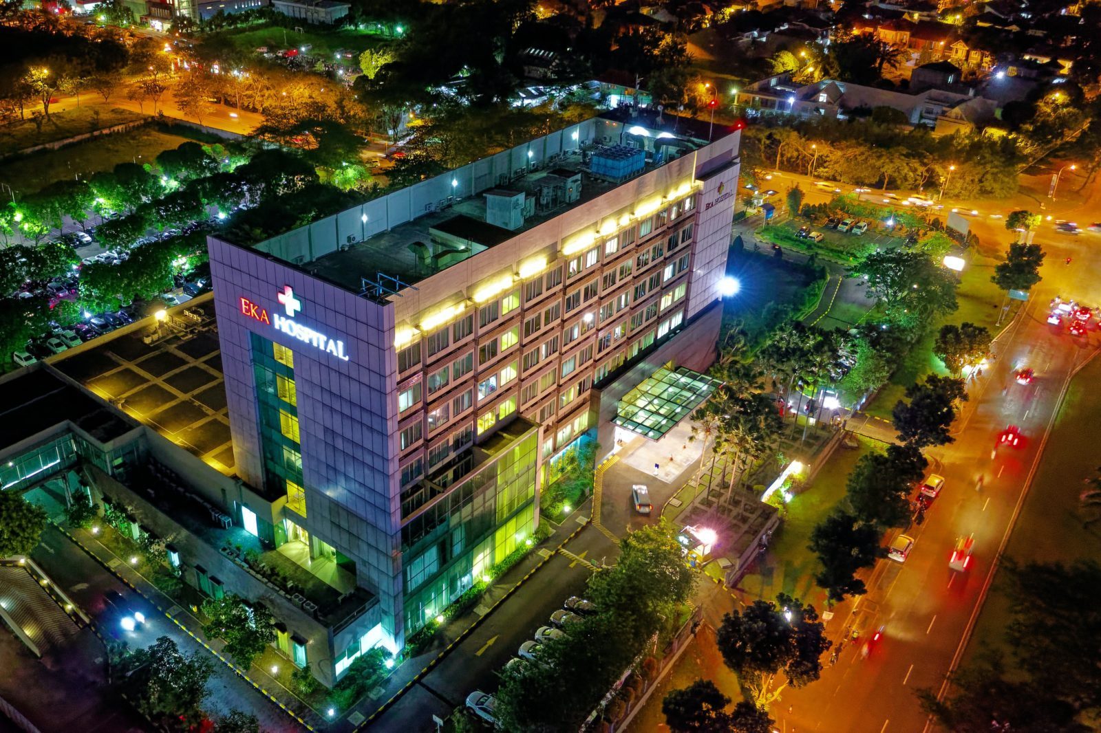 hospital-beside-vehicle-park-and-road-at-night-1692693